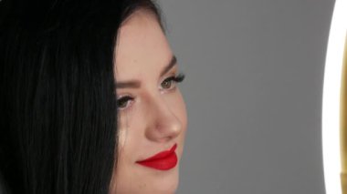 Büyük dudakları kırmızı rujla boyanmış güzel kız modelin yakın görüntüsü. Parlak makyajlı genç bir kadın..