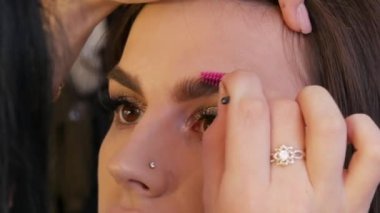 Fırça, kaşlara gölge sürerek güzel, genç bir modelin şeklini düzeltir. Smoky eyes için akşam makyajı için..