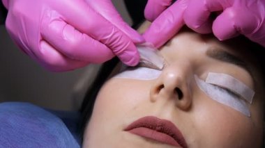 Profesyonel bir güzellik salonunda modern kirpik kaplama prosedürü. Usta kirpik kıvırma işleminden önce özel silikon bigudiler uyguluyor..