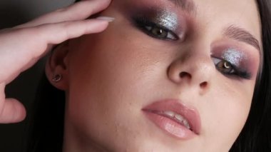 Şık makyajlı, dumanlı, poz veren ve gülümseyen güzel genç kız modeli, gri arka planda yüksek moda..