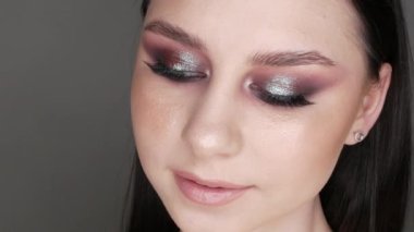 Şık makyajlı, dumanlı, poz veren ve gülümseyen güzel genç kız modeli, gri arka planda yüksek moda..