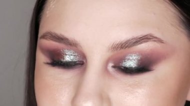 Şık makyajlı, dumanlı, poz veren ve gülümseyen güzel genç kız modeli, gri arka planda yüksek moda..