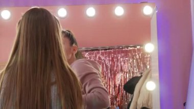 Make-up artist applies modern make-up on the face of a young girl model in the studio.