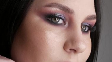 Şık makyajlı, dumanlı, poz veren ve gülümseyen güzel genç kız modeli, gri arka planda yüksek moda..