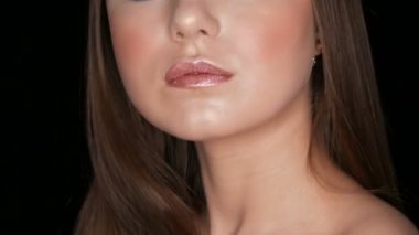 Portrait of a very beautiful long-haired delightful young girl model with beautifully painted lips posing in front of the camera on a stylish black background.