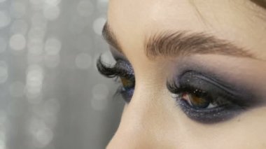 Portrait of a very beautiful young girl model with bright evening make-up, smoky eyes posing in front of camera on a stylish black background close up