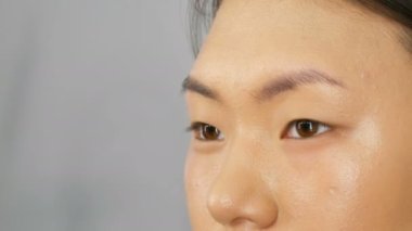 Profesyonel makyaj sanatçısı özel bir fırça ile Asya Koreli modeller yüz vakıf kapatıcı veya vurgulayıcı uygular