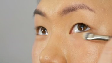 Profesyonel makyaj sanatçısı özel bir fırça ile Asya Koreli modeller yüz vakıf kapatıcı veya vurgulayıcı uygular