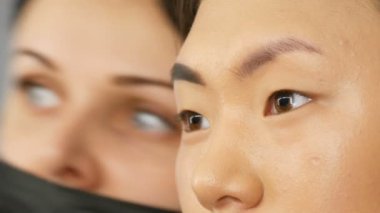 Profesyonel makyaj sanatçısı özel bir fırça ile Asyalı Koreli kadın modelin yüzüne kaşboyaları.