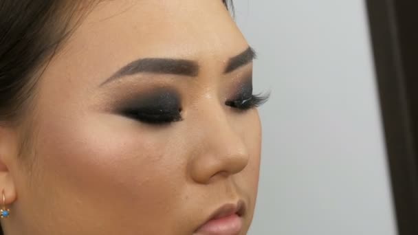 专业化妆师在美容院里将假睫毛贴在一名亚洲韩国妇女的眼睛上 — 图库视频影像