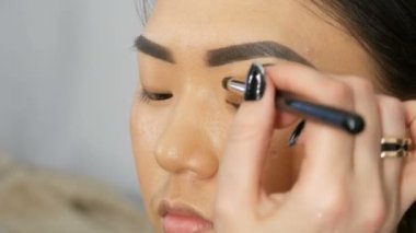 Profesyonel makyöz, Koreli Asyalı bir kızın özel fırçasıyla göz makyajı yapıyor.