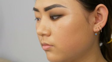 Profesyonel makyöz, Koreli Asyalı bir kızın özel fırçasıyla göz makyajı yapıyor.