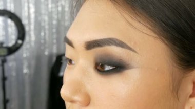 Profesyonel makyöz, Koreli Asyalı bir kızın özel fırçasıyla göz makyajı yapıyor.