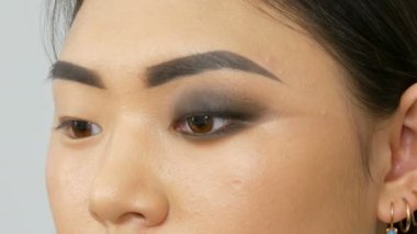 Profesyonel makyöz, Koreli Asyalı bir kızın özel fırçasıyla göz makyajı yapıyor.