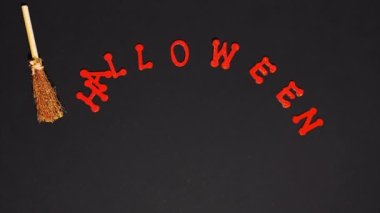 Stop motion animation. Puppet broom sweeps the word halloween on a black background. The end of the holiday