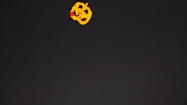Stop motion animation Halloween. Funny cute smile felt cartoon pumpkin appear and disappear on a black background. Stop motion animation. Autumn concept.