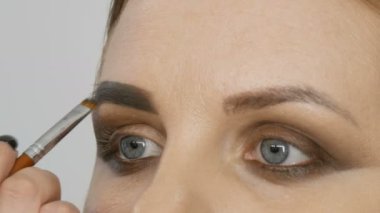 Profesyonel akşam makyajı, özel bir fırça kaş şeklini değiştirir. Makyöz, genç bir kadın mankene kaş çizer..
