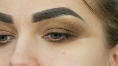 Profesyonel makyöz, kahverengi bir gölgenin dumanlı gözlerini yeşil gözlü güzel bir modelin özel fırçasıyla yapar.