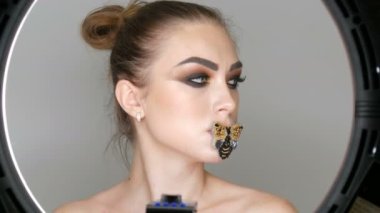 Güzel, profesyonel bir kız modelin portresi şık dumanlı göz makyajı ve stüdyoda kameranın önünde poz veren dudaklarında kelebek. Yüksek moda.