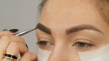 Makyaj sanatçısı, model kızları güzellik salonunda profesyonel makyaj malzemesi yapar. Özel bir fırçayla kaş çizimi