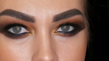 Stüdyoda kameranın önünde poz veren şık dumanlı göz makyajlı güzel bir profesyonel kız modelinin yüz portresi. Yüksek moda.