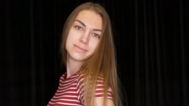 Güzel, uzun saçlı, sorunlu bir kız kameranın önünde poz veriyor.