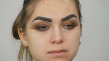 Profesyonel makyöz, kahverengi bir gölgenin dumanlı gözlerini yeşil gözlü güzel bir modelin özel fırçasıyla yapar.