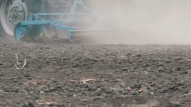 Mavi traktör ilkbaharda tarlaları dikmeden önce toprağı sürer.