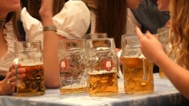 Münih, Almanya - 17 Eylül 2022: Dünyaca ünlü bira festivalinin ilk günü, Oktoberfest. İnsanlar çadırda oturur, bira içer, yer ve kutlarlar. Bira dolu büyük bir litre bardak..