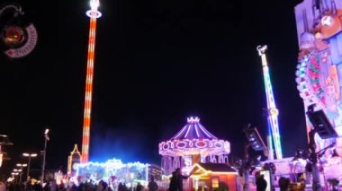 Münih, Almanya - 17 Eylül 2022: Renkli parlayan binişler, atlıkarıncaların ve salıncakların gece görüşü. Dünyaca ünlü bira festivali Oktoberfest 'in ziyaretçileri. Theresienwiese 'deki kalabalık.