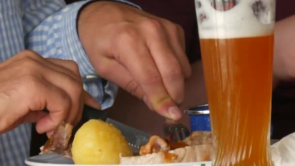 Oktoberfest帐篷 一个男人喝了一杯啤酒 拿着一把刀叉吃着传统的猪肉 泡菜和油炸土豆 德国慕尼黑 — 图库视频影像