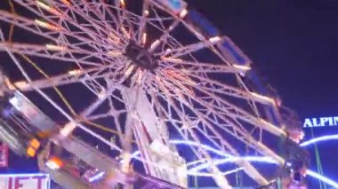Münih, Almanya - 17 Eylül 2022: Renkli parlayan binişler, atlıkarıncaların ve salıncakların gece görüşü. Dünyaca ünlü bira festivali Oktoberfest 'in ziyaretçileri. Theresienwiese 'deki kalabalık.