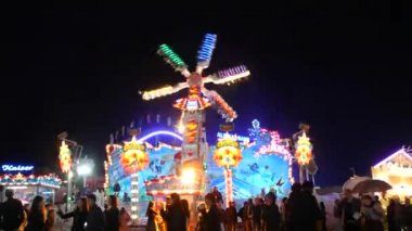 Münih, Almanya - 17 Eylül 2022: Renkli parlayan binişler, atlıkarıncaların ve salıncakların gece görüşü. Dünyaca ünlü bira festivali Oktoberfest 'in ziyaretçileri. Theresienwiese 'deki kalabalık.