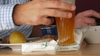 Oktoberfest çadırları. Bir adam bir bardak bira içer ve bıçak ve çatalla geleneksel domuz budu ile lahana turşusu ve kızarmış patates yer. Münih, Almanya.