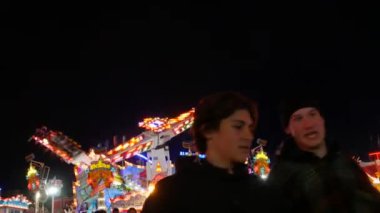 Münih, Almanya - 17 Eylül 2022: Renkli parlayan binişler, atlıkarıncaların ve salıncakların gece görüşü. Dünyaca ünlü bira festivali Oktoberfest 'in ziyaretçileri. Theresienwiese 'deki kalabalık.