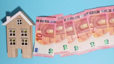 Hareket animasyonunu durdurun. Avro parası. Finansal kriz. Doku. Finans İşletmeleri Yatırım Başarı Konsepti. Ahşap ev ve Avro parası. Mavi arka planda en üstten 10 euro görünüyor..