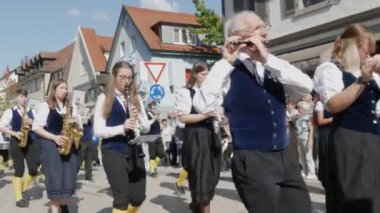 Buhl, Almanya - 11 Eylül 2022: Şehir sokaklarındaki erik hasadının onuruna düzenlenen şenlik geçidi. Mavi ve beyaz giyinmiş bir bando sokakta yürüyor, seyirciler izliyor..