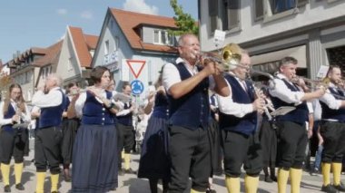 Buhl, Almanya - 11 Eylül 2022: Şehir sokaklarındaki erik hasadının onuruna düzenlenen şenlik geçidi. Mavi ve beyaz giyinmiş bir bando sokakta yürüyor, seyirciler izliyor..