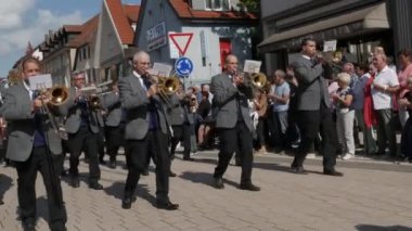 Buhl, Almanya - 11 Eylül 2022: Şehir sokaklarındaki erik hasadının onuruna düzenlenen şenlik geçidi. Gri ceketli bir bando sokakta yürüyor, seyirciler izliyor..