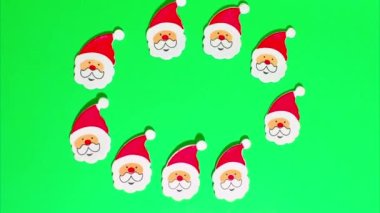 Noel Hareketi animasyonu, kırmızı şapkalı, beyaz sakallı ve bıyıklı bir sürü komik Noel Baba yeşil renkli anahtar arka planda hareket ediyor..