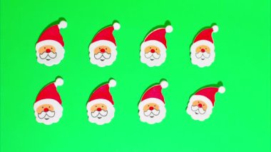 Noel Hareketi animasyonu, kırmızı şapkalı, beyaz sakallı ve bıyıklı bir sürü komik Noel Baba yeşil renkli anahtar arka planda hareket ediyor..