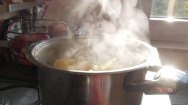 Buhar ya da Buhar bulutları ocaktaki tencerede kaynar sudan yükseliyor. Patates pişirirken tavadan buhar çıkıyor. Ev mutfağında aşçılık süreci.