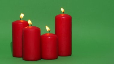 Yeşil krom anahtar arka planında koyu kırmızı Noel mumları. Mum alevi yanıyor ve dans ediyor..