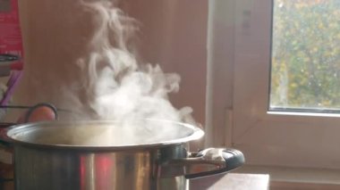 Buhar ya da Buhar bulutları ocaktaki tencerede kaynar sudan yükseliyor. Patates pişirirken tavadan buhar çıkıyor. Ev mutfağında aşçılık süreci.