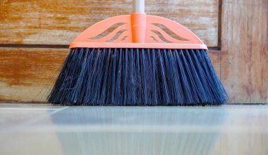 Yerleri süpürmek için gri tüylü sarı plastik süpürge seti ve beyaz arka planda faraş, seçici odak noktasında çalışan kısımlar.