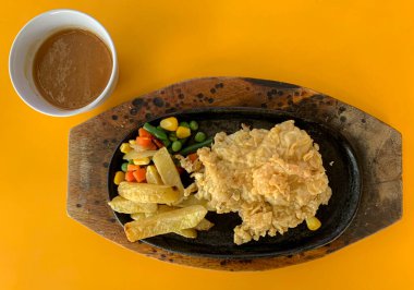 Beef steak with wheat flour, vegetables and sauce on orange table
