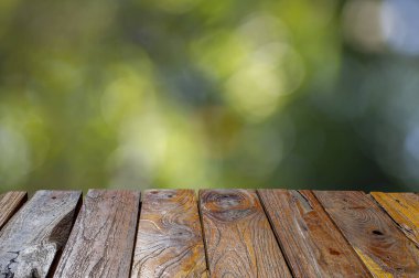 Ürünün gösterimi için yeşil bokeh arkaplanının önündeki eski meşe ağacı boş masa