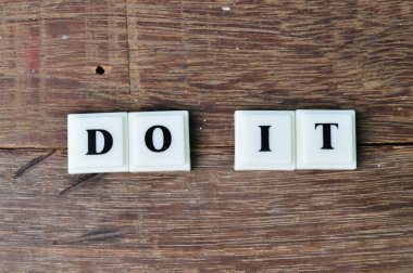 Ahşap bir arkaplanda izole edilmiş metni olan kare harfler.