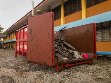 Binanın dışında çöp yığını olan metal çöp kutusu.