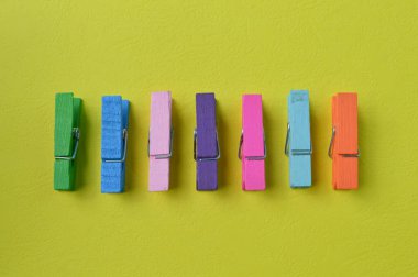 Sarı arka planda izole edilmiş renkli mandallar